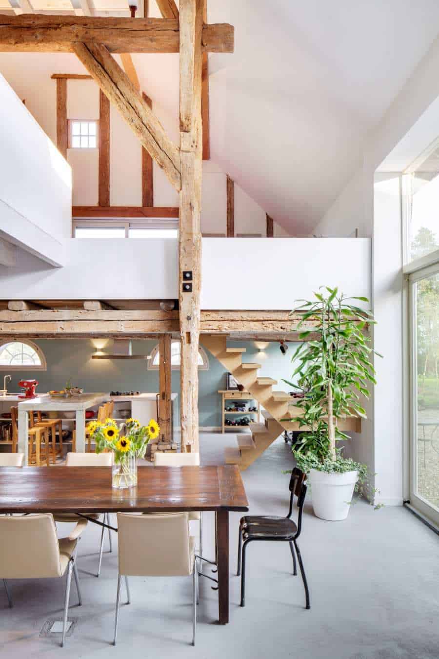 Moderne woonkamer met houten balken en zwevende trap.